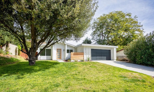 view of front of house with a garage, board and batten siding, fence, concrete driveway, and a front lawn