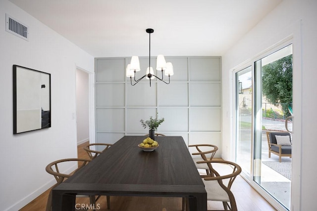 dining area with visible vents, light wood-style flooring, an inviting chandelier, and baseboards