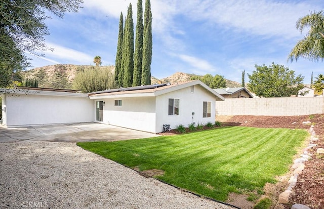 back of property featuring stucco siding, a patio area, solar panels, a yard, and fence