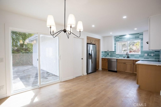 kitchen with tasteful backsplash, appliances with stainless steel finishes, an inviting chandelier, and a healthy amount of sunlight