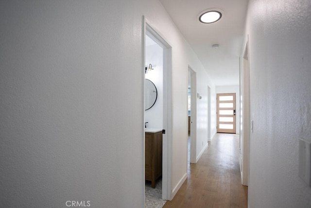 corridor with light wood finished floors and baseboards