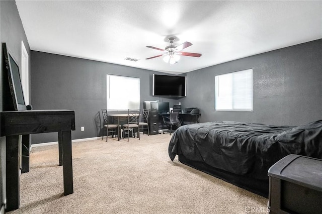 carpeted bedroom with visible vents, multiple windows, baseboards, and ceiling fan