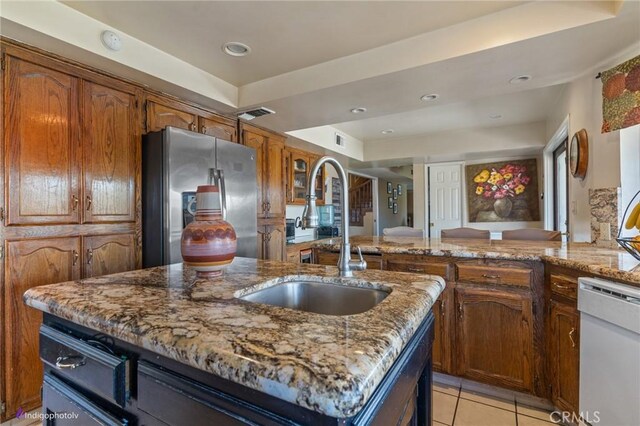 6351 Deacon Ave, Bakersfield, CA 93307 - kitchen with a center island with sink, a sink, stainless steel fridge, light tile patterned floors, and dishwasher