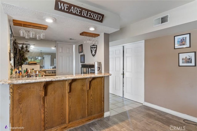 6351 Deacon Ave, Bakersfield, CA 93307 - kitchen with visible vents, baseboards, light stone counters, wood finished floors, and a textured ceiling