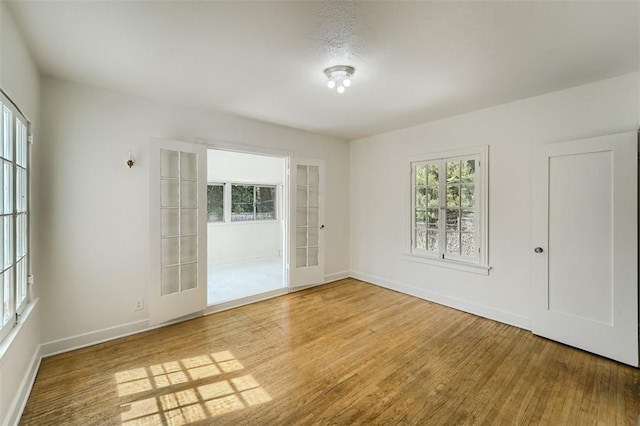 spare room with baseboards and wood finished floors