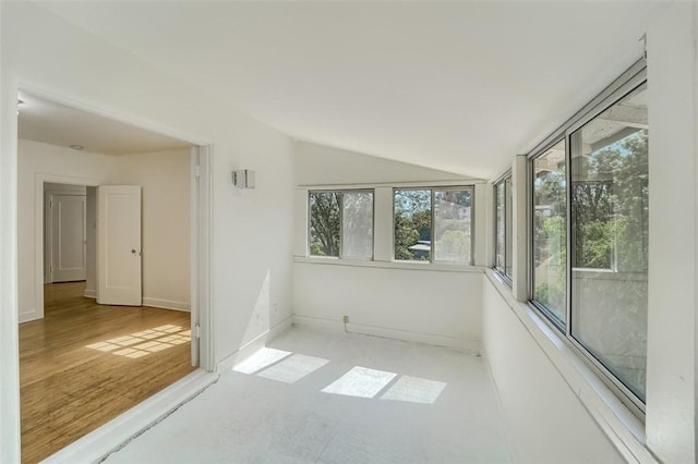 unfurnished sunroom with vaulted ceiling, a healthy amount of sunlight, and baseboards