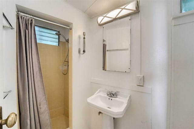 bathroom featuring a shower stall, ornamental molding, and a sink