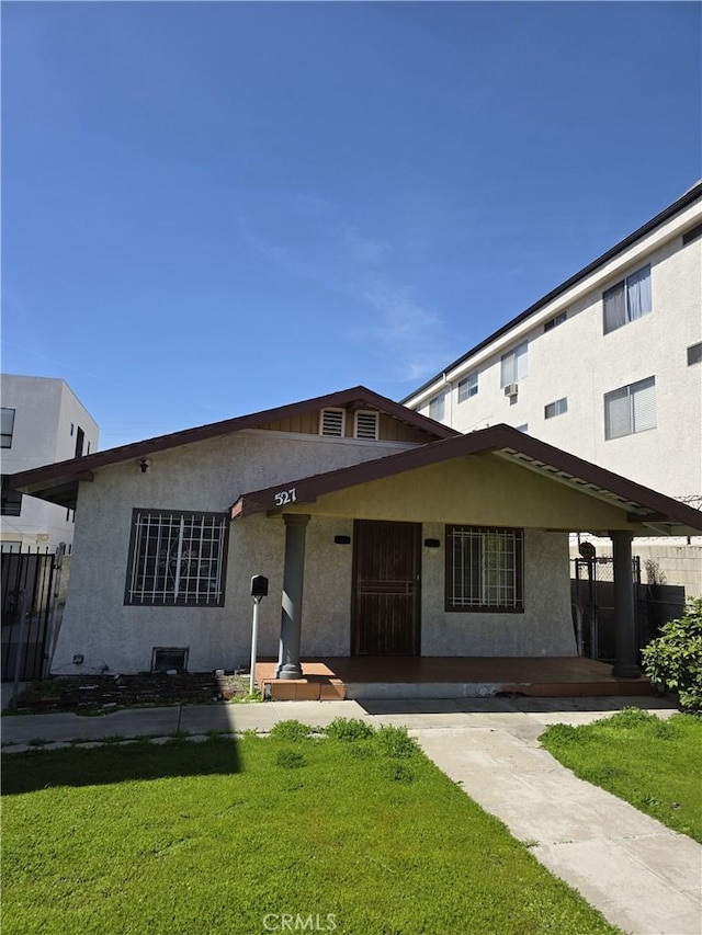 view of front of house with a front lawn, fence, and stucco siding
