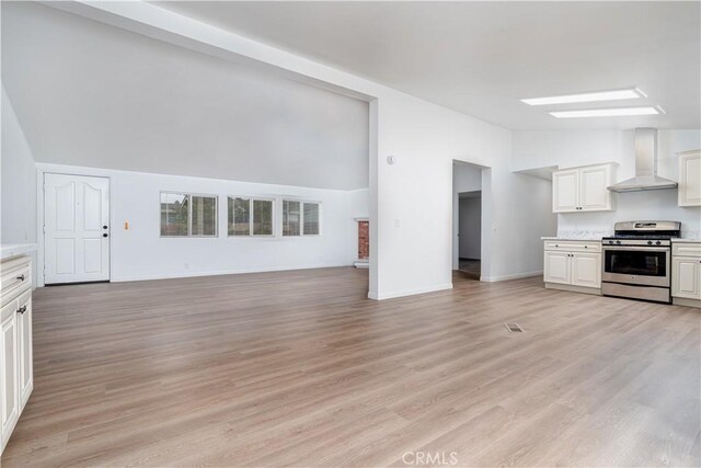 1357 Mount Shasta St, Perris, CA 92570 - kitchen featuring gas range, wall chimney exhaust hood, open floor plan, light countertops, and light wood-type flooring