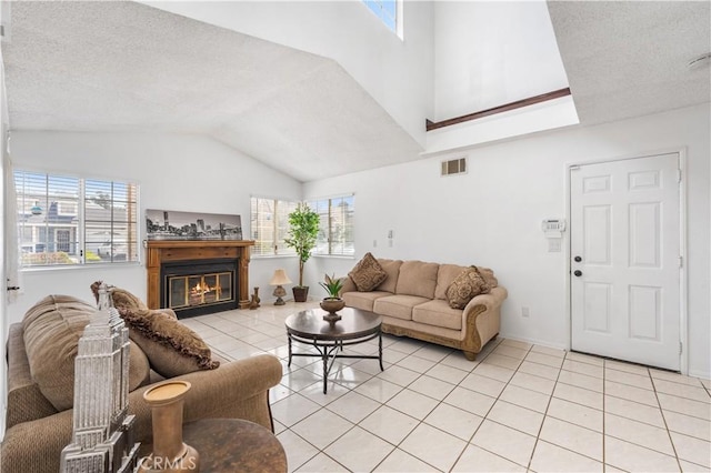 42851 Lemonwood Dr, Lancaster, CA 93536 - living room featuring vaulted ceiling, light tile patterned flooring, a glass covered fireplace, and a textured ceiling
