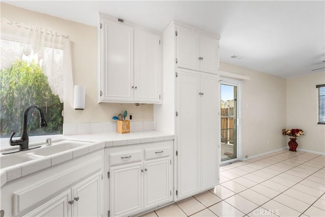 42851 Lemonwood Dr, Lancaster, CA 93536 - kitchen with white cabinetry, tile counters, light tile patterned floors, and healthy amount of natural light