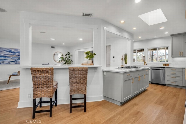 kitchen featuring visible vents, gray cabinetry, gas cooktop, and stainless steel dishwasher
