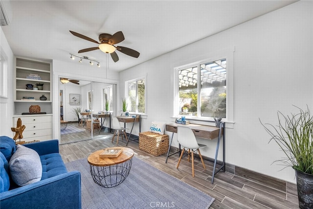 living area featuring baseboards, ceiling fan, wood tiled floor, and a wall unit AC