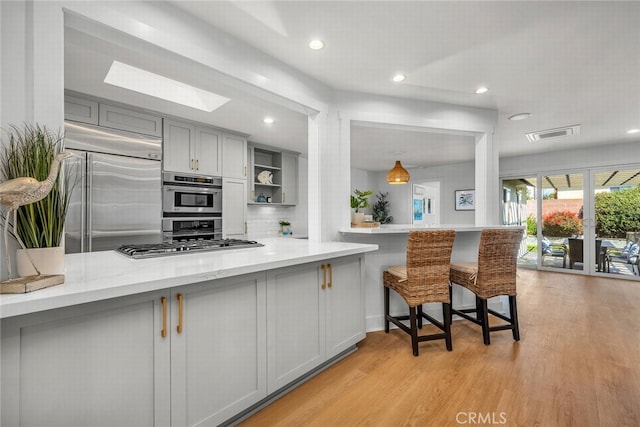 kitchen with visible vents, gray cabinetry, appliances with stainless steel finishes, a skylight, and light wood finished floors