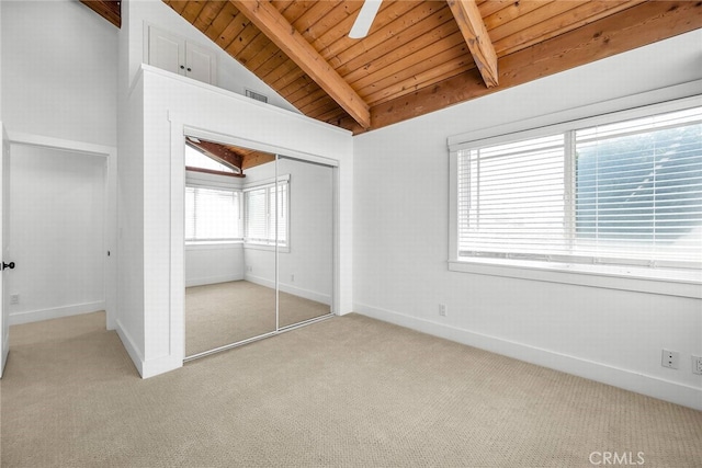 unfurnished bedroom featuring visible vents, baseboards, light colored carpet, lofted ceiling with beams, and a closet