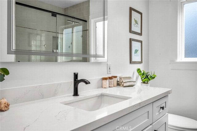 bathroom with vanity, a shower stall, toilet, and a healthy amount of sunlight