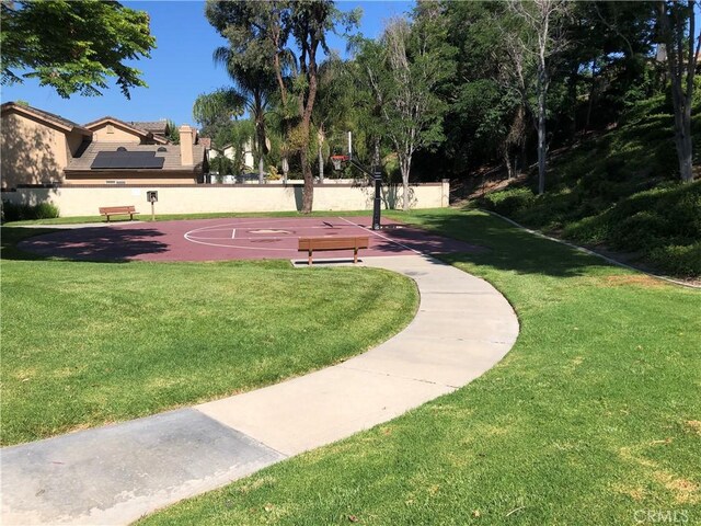 view of community featuring community basketball court and a yard