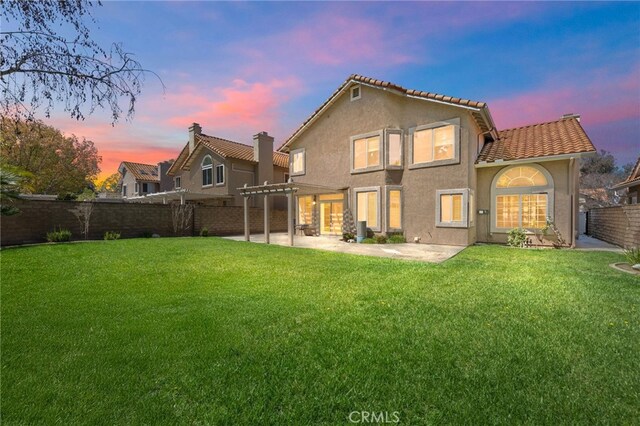 back of property with a pergola, stucco siding, a fenced backyard, a patio area, and a yard
