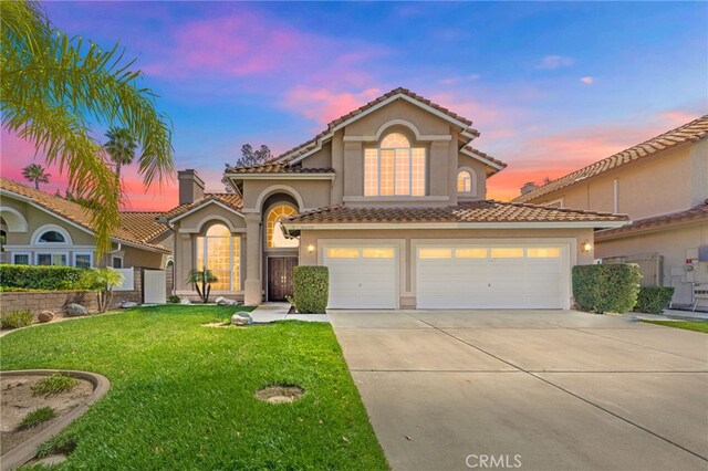 mediterranean / spanish-style house with a yard, stucco siding, concrete driveway, and a tiled roof