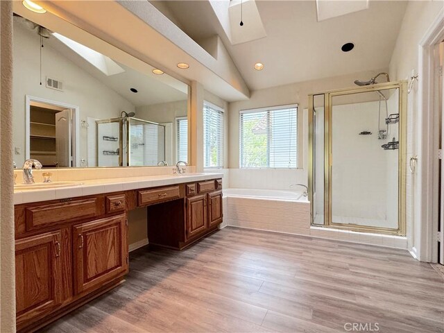 full bath featuring visible vents, wood finished floors, a bath, vaulted ceiling with skylight, and a stall shower