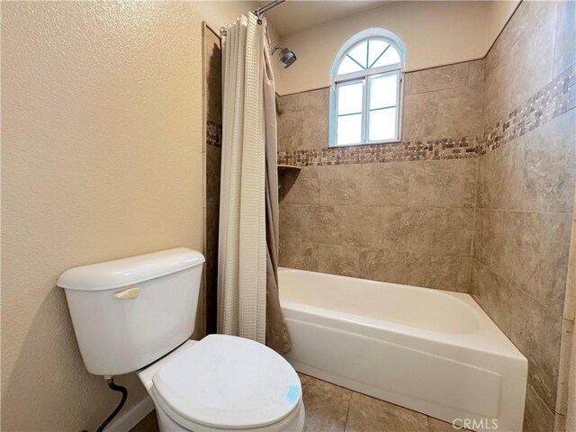 bathroom featuring toilet, shower / bath combo, and tile patterned flooring