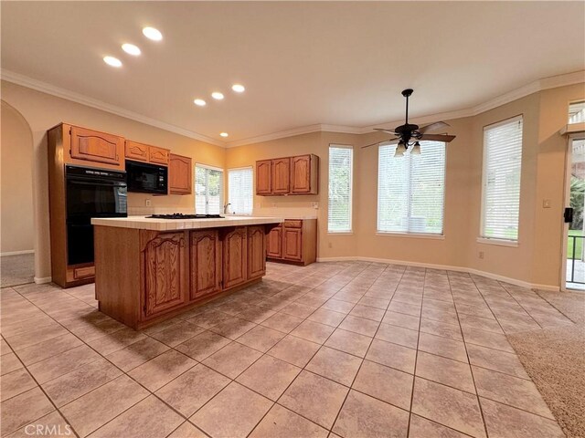 kitchen with a center island, light countertops, light tile patterned floors, and black appliances