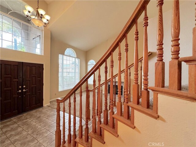 entrance foyer with an inviting chandelier, baseboards, stairway, tile patterned floors, and vaulted ceiling