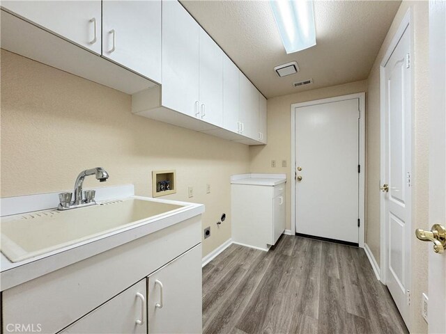 laundry room with cabinet space, washer hookup, a sink, light wood-style flooring, and visible vents
