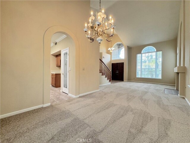 foyer entrance featuring carpet flooring, baseboards, high vaulted ceiling, a chandelier, and arched walkways