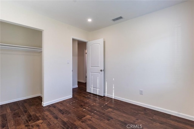 unfurnished bedroom featuring a closet, baseboards, recessed lighting, visible vents, and wood finished floors