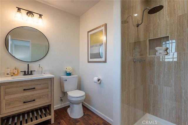 bathroom featuring tiled shower, vanity, toilet, and wood finished floors