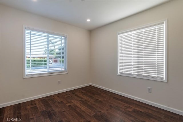 empty room with dark wood-style flooring, baseboards, and recessed lighting