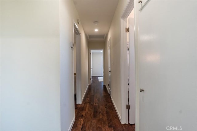 hallway with dark wood-type flooring, attic access, and baseboards