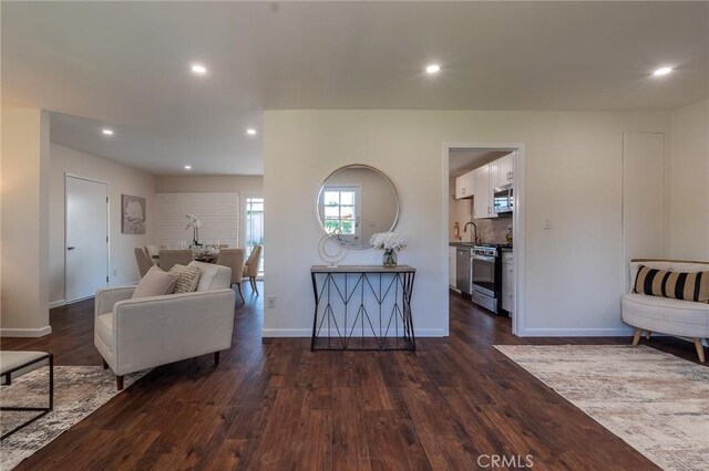 living area featuring dark wood-style flooring, baseboards, and recessed lighting