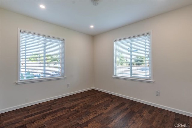 unfurnished room with a wealth of natural light, dark wood-style floors, and baseboards