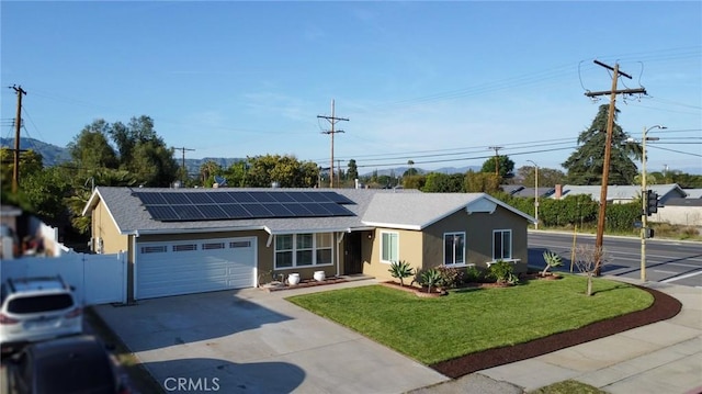 ranch-style house featuring driveway, a front yard, a garage, fence, and roof mounted solar panels
