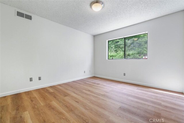 28951 Spring Valley Rd, Tollhouse, CA 93667 - empty room with visible vents, a textured ceiling, light wood-type flooring, and baseboards