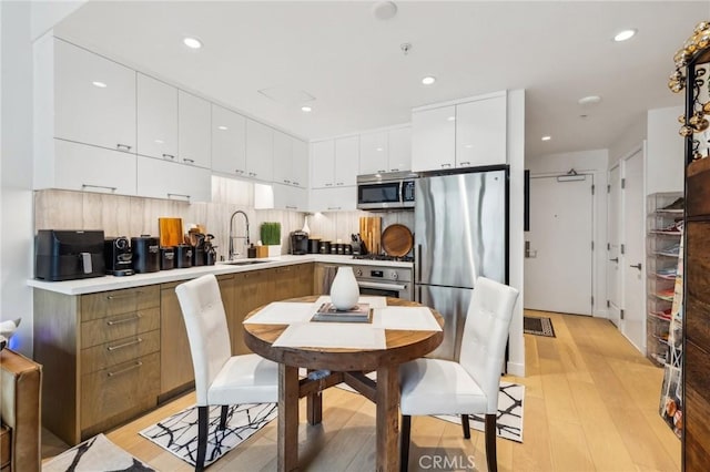 400 S Broadway Unit 1011, Los Angeles, CA 90013 - kitchen with appliances with stainless steel finishes, a sink, white cabinetry, light wood-type flooring, and modern cabinets