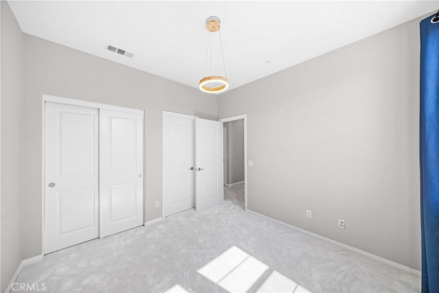 unfurnished bedroom featuring baseboards, visible vents, carpet floors, and a closet