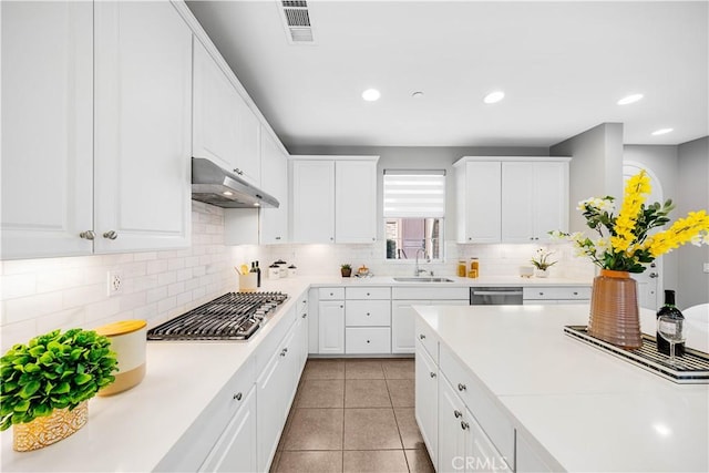kitchen featuring under cabinet range hood, a sink, stainless steel appliances, light countertops, and light tile patterned floors