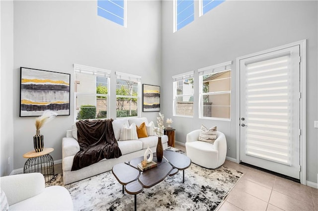living room featuring tile patterned floors, a high ceiling, baseboards, and a wealth of natural light