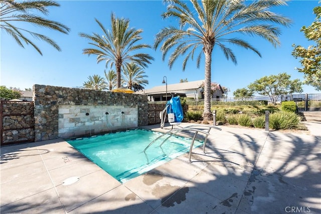 view of swimming pool with a patio area, a pool, and fence