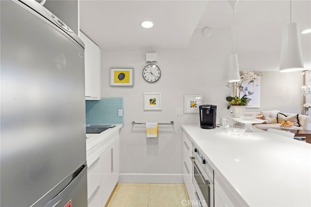kitchen with light countertops, stainless steel fridge, light tile patterned floors, decorative backsplash, and white cabinets