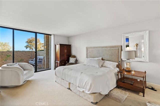 carpeted bedroom with baseboards, access to exterior, and a wall of windows