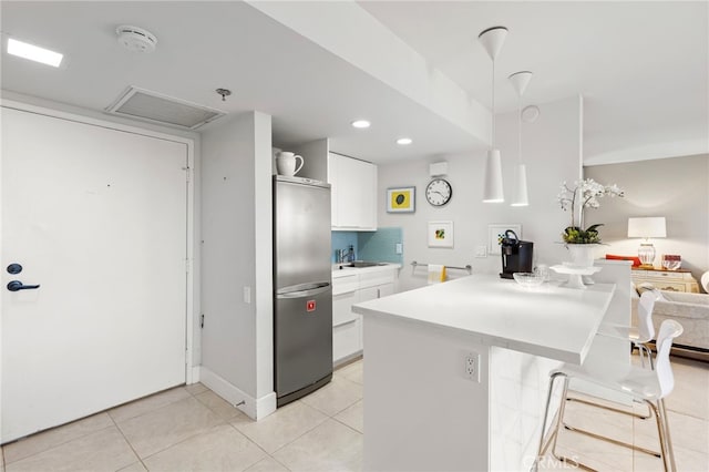 kitchen with white cabinetry, light countertops, a breakfast bar, light tile patterned flooring, and freestanding refrigerator