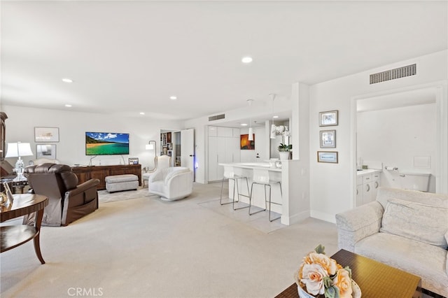 living area featuring light colored carpet, visible vents, baseboards, and recessed lighting