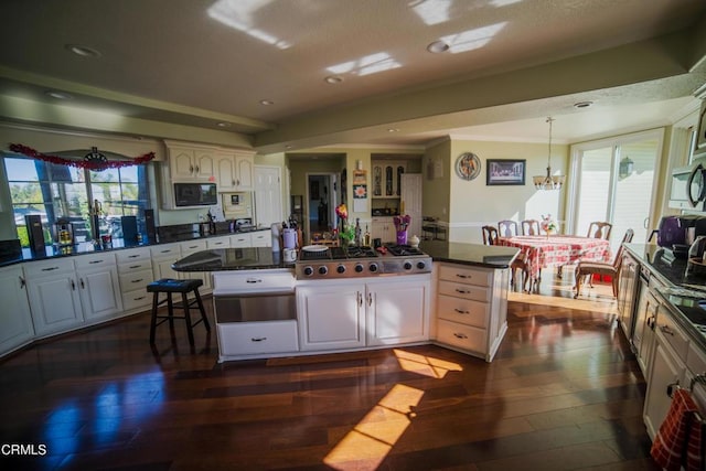 600 Monte Vista Dr, Santa Paula, CA 93060 - kitchen featuring a kitchen island, dark countertops, dark wood finished floors, stainless steel gas stovetop, and black microwave