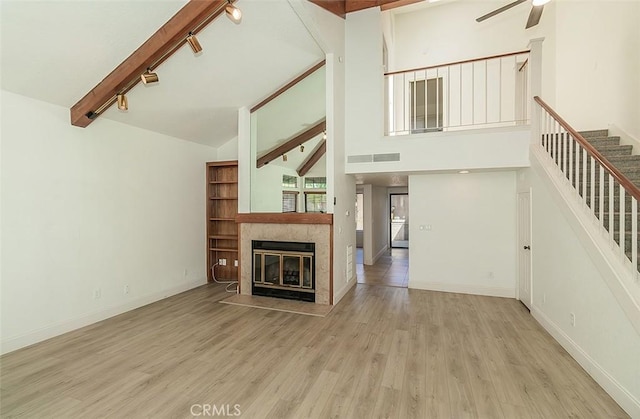 712 E Magill Ave, Fresno, CA 93710 - unfurnished living room with rail lighting, ceiling fan, stairs, wood finished floors, and beam ceiling