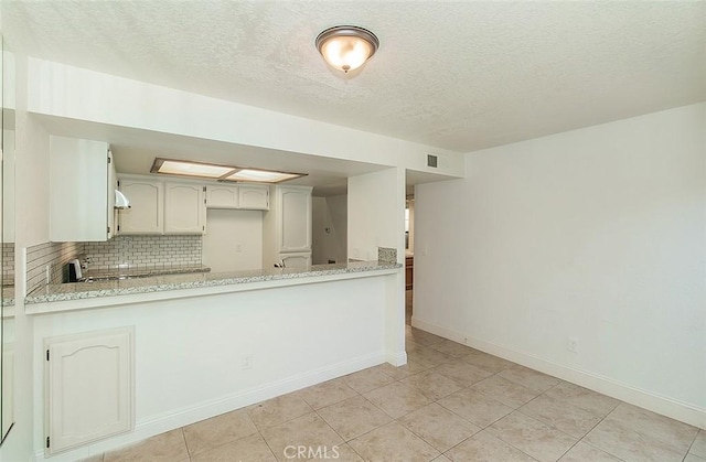 712 E Magill Ave, Fresno, CA 93710 - kitchen featuring tasteful backsplash, light tile patterned flooring, a textured ceiling, a peninsula, and light stone counters