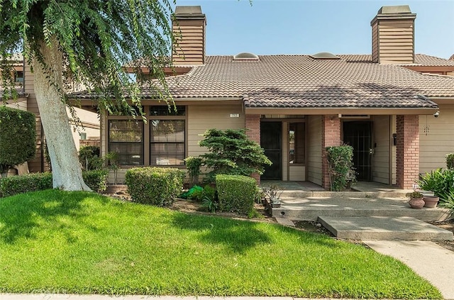 712 E Magill Ave, Fresno, CA 93710 - view of front of home featuring a chimney, a tile roof, a front lawn, and brick siding